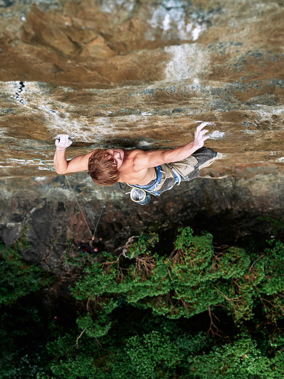 Rock climber grimaces on rock face climb
