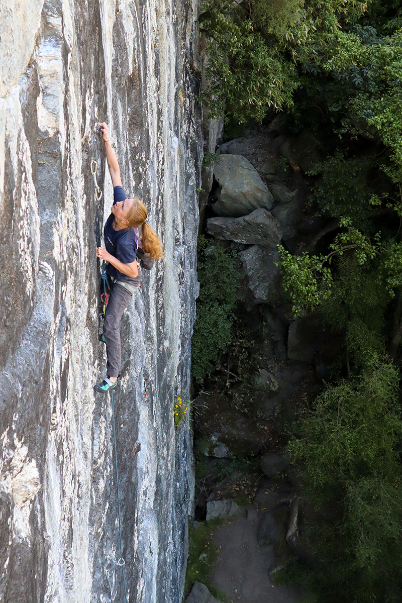 Rock climber grimaces on rock face climb