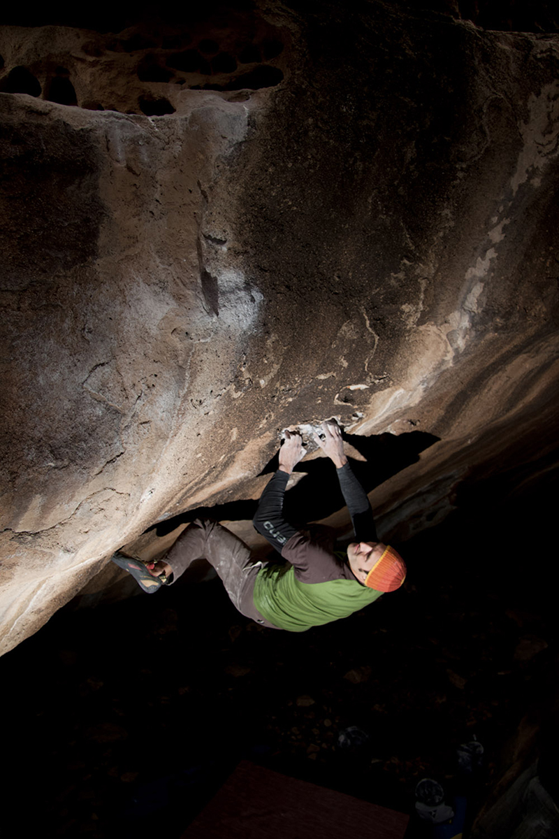 Boulderer on orange stone
