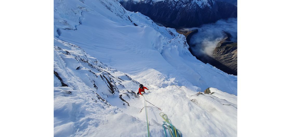 Alpine climber snow face valley of cloud