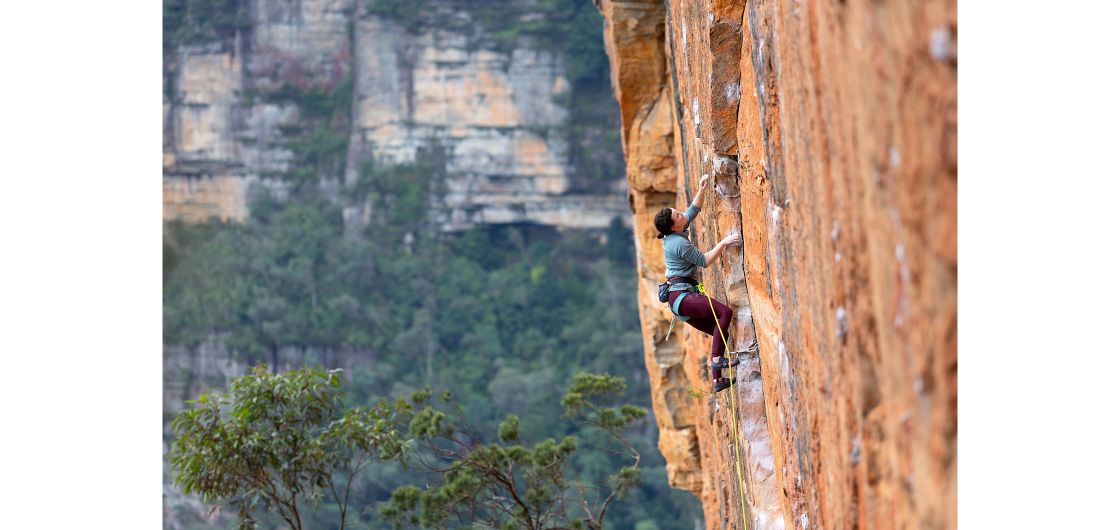 Female rock climber on orange sandstone sport route