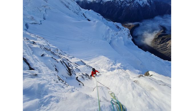 Alpine climber snow face valley of cloud