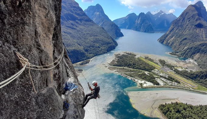 Climber on big wall above fiords.