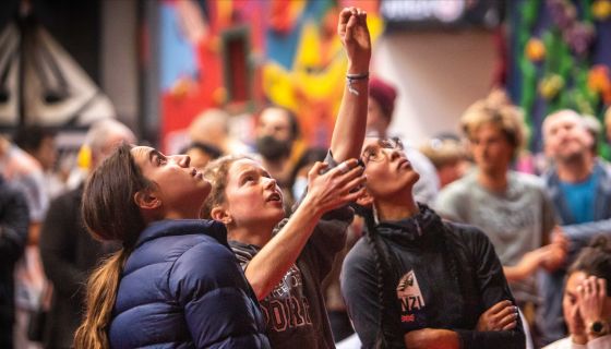 Competition climbers observe a route from the ground, miming sequences.