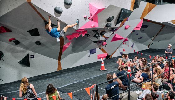 Climber on competition boulder with crowd watching