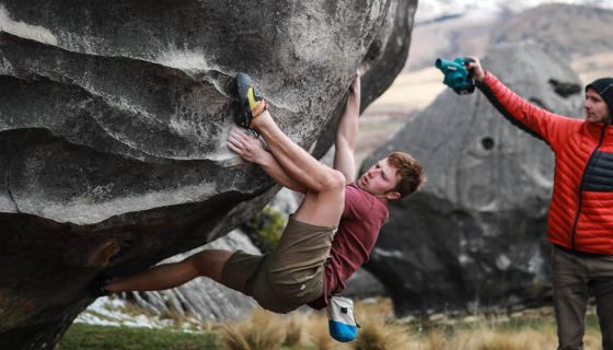 Climber on slopey holds of boulder problem